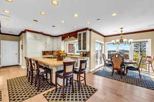 Dining space with light wood-style flooring, hanging lights, and ornamental molding
