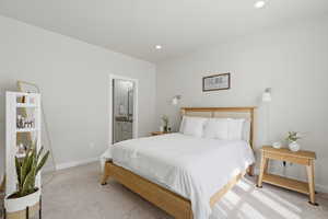 Bedroom featuring light colored carpet, ensuite bathroom, and recessed lighting