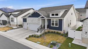 View of front of house featuring a shingled roof, concrete driveway, stone siding, a gate, and a standing seam roof