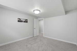 Spare room featuring a textured ceiling and light carpet
