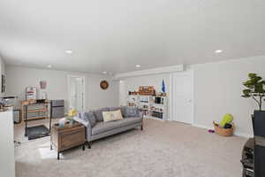 Living room with light colored carpet, recessed lighting, and a textured ceiling