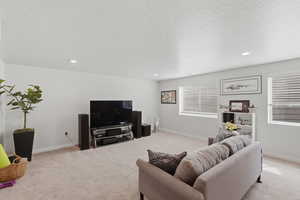 Living room featuring light colored carpet, a textured ceiling, plenty of natural light, and recessed lighting