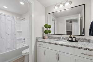 Full bath featuring vanity, shower / bath combination with curtain, and wood finished floors