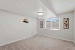 Empty room with light carpet and a textured ceiling