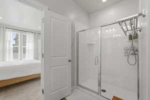 Ensuite bathroom with a shower stall, light colored carpet, and recessed lighting