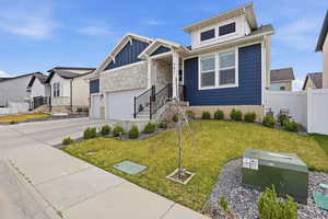View of front of home with board and batten siding, a front lawn, stone siding, driveway, and a residential view
