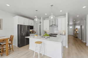 Kitchen featuring stainless steel appliances, white cabinetry, a center island with sink, and a kitchen breakfast bar