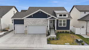 View of front facade with concrete driveway, a garage, stone siding, a shingled roof, and a gate