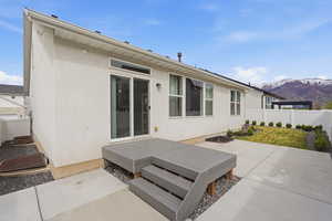 Rear view of property featuring a fenced backyard, a mountain view, stucco siding, and a patio