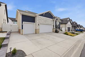 View of front of house with a gate, board and batten siding, a garage, concrete driveway, and a residential view