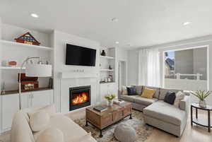 Living area with wood finished floors, built in features, a tile fireplace, recessed lighting, and a textured ceiling