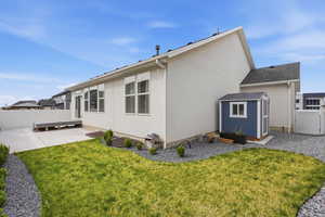 Back of property with a fenced backyard, stucco siding, and a shed