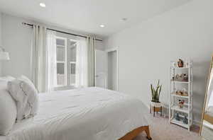 Bedroom with light colored carpet and recessed lighting