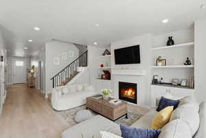 Living room with light wood finished floors, a fireplace, recessed lighting, and a textured ceiling