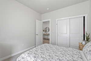 Carpeted bedroom with baseboards and a closet