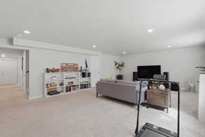 Living room with light carpet, recessed lighting, and a textured ceiling
