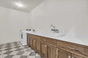 Laundry area featuring light flooring, washing machine and dryer, and cabinet space