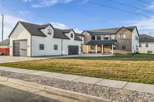 View of front facade featuring a porch, a front lawn, brick siding, and concrete driveway