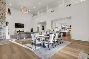 Dining room with arched walkways, a chandelier, light wood finished floors, and a high ceiling
