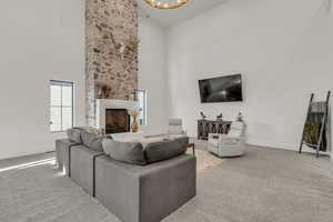 Carpeted living room featuring a fireplace, vaulted ceiling, and hanging lights