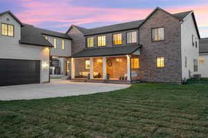 Back of house with a porch, a yard, brick siding, and concrete driveway