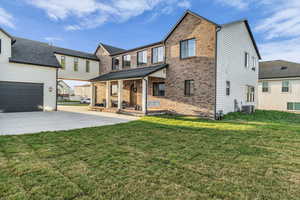 Traditional home with covered porch, a front lawn, brick siding, a garage, and concrete driveway