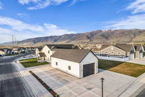 View of front of house featuring a residential view, a mountain view, roof with shingles, concrete driveway, and stucco siding