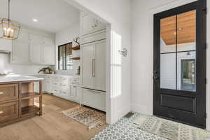 Kitchen featuring open shelves, two tone cabinets, paneled refrigerator, and suspended lighting