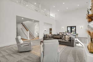Living area featuring recessed lighting, a high ceiling, and light carpet