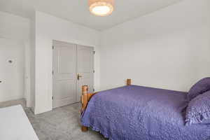 Bedroom with light colored carpet and a closet