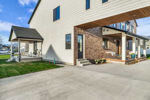 Entrance to property with a patio area, a shingled roof, a yard, and brick siding