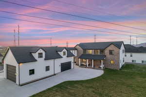 Modern farmhouse featuring covered porch, a garage, a front yard, driveway, and roof with shingles