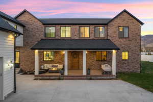 Rear view of house featuring covered porch, brick siding, a shingled roof, and outdoor lounge area