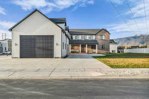 Traditional home with a porch, an attached garage, a mountain view, concrete driveway, and brick siding
