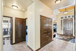 Foyer with light tile patterned floors and a tray ceiling