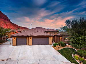 Mediterranean / spanish home featuring stucco siding, a garage, driveway, and a tiled roof
