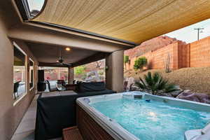 Fenced backyard with a patio area, a ceiling fan, a hot tub, and area for grilling