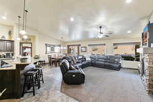 Living area with a stone fireplace, a ceiling fan, lofted ceiling, recessed lighting, and light carpet
