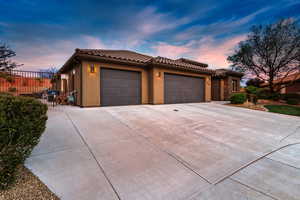 View of front facade featuring stucco siding, a garage, concrete driveway, and a tiled roof