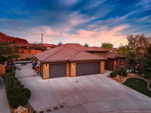 Mediterranean / spanish home featuring a garage, driveway, stucco siding, and a gate