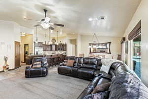 Living area with ceiling fan, light carpet, and a high textured ceiling