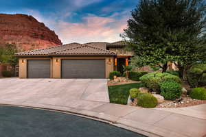 View of front of home with a garage, concrete driveway, stucco siding, and a tile roof