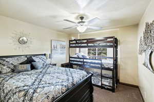 Bedroom with dark carpet, a ceiling fan, and a textured ceiling