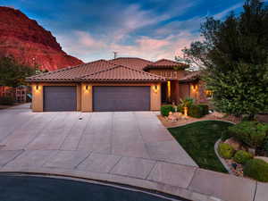 Mediterranean / spanish-style home with a garage, stucco siding, driveway, and a tile roof