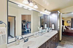 Full bath with ensuite bathroom, double vanity, and a spacious closet