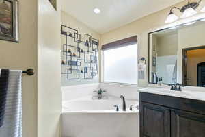 Bathroom with a bath, vanity, and recessed lighting
