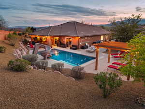 Pool at dusk featuring outdoor seating, a patio, a water slide, and a fenced backyard
