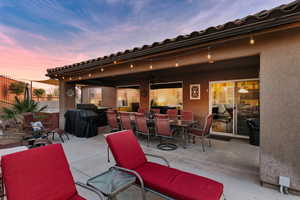 Patio terrace at dusk featuring a patio area, a ceiling fan, outdoor dining area, and grilling area