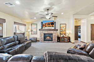 Carpeted living area with a fireplace and a ceiling fan
