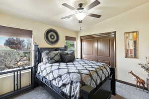 Bedroom with a closet, lofted ceiling, ceiling fan, and dark carpet